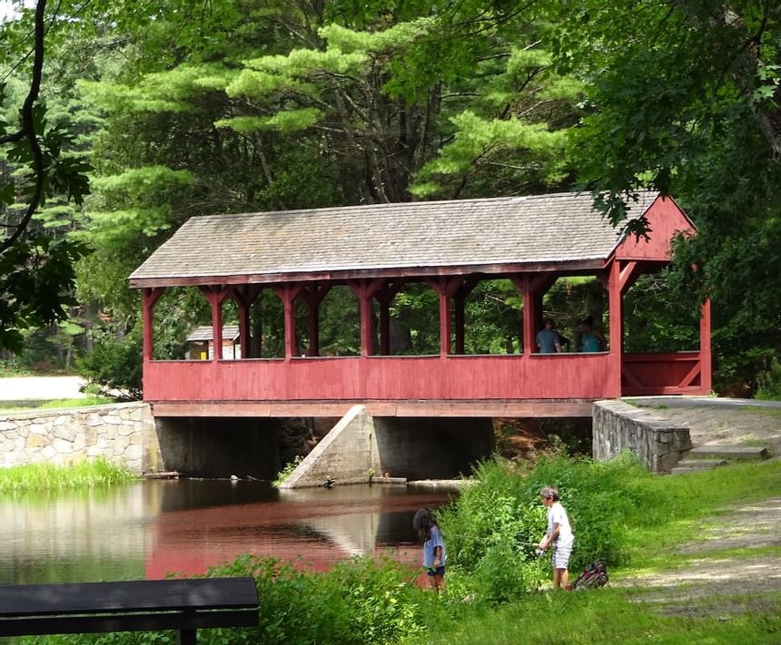 Stratton Brook State Park with a red-covered bridge over a calm river and two children near Avon Old Farms Hotel