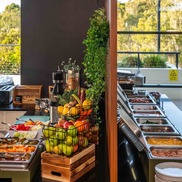 Buffet Breakfast with fresh fruits, juices, and hot dishes by a window at Mercure Kooindah Waters