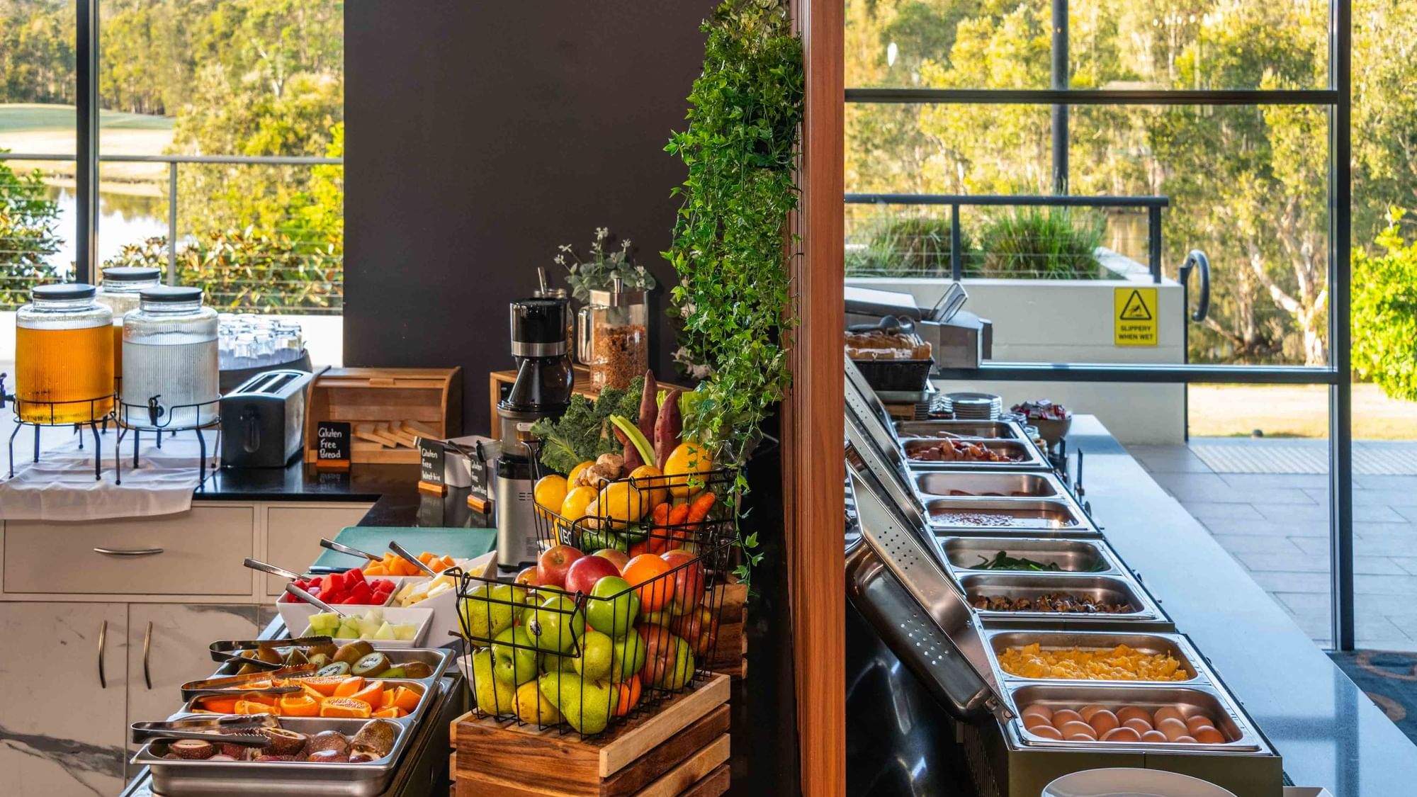 Buffet Breakfast with fresh fruits, juices, and hot dishes by a window at Mercure Kooindah Waters