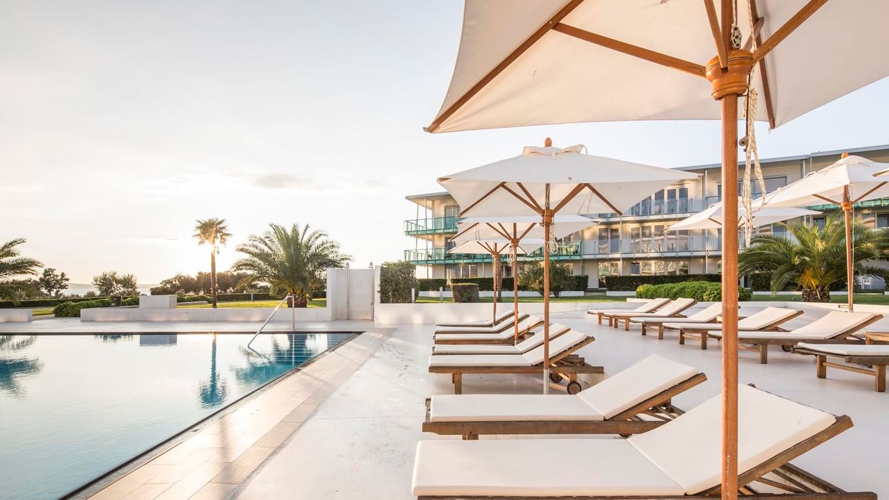 Sunbeds by the pool on a bright day at Falkensteiner Hotels