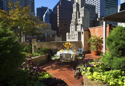 Garden Terrace rooftop garden with table, chairs, flowers, and urban skyline view.