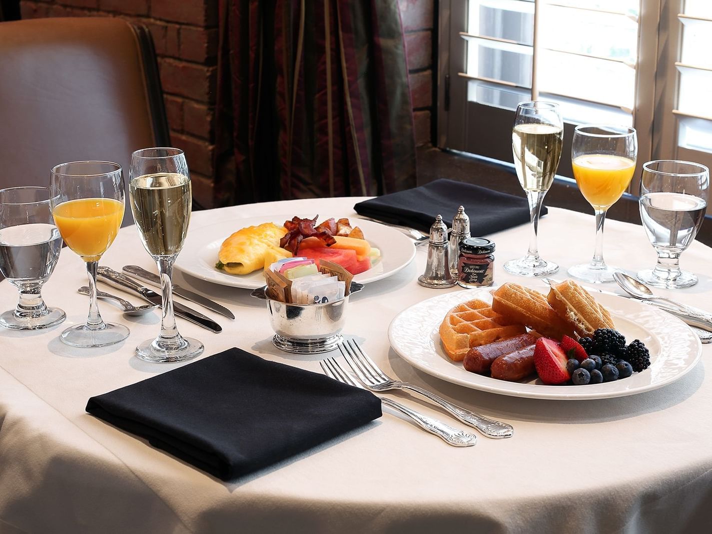 table with two breakfast plates, with champagne and orange juice