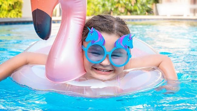 Chica sobre un flotador de flamencos en la piscina al aire libre, Live Aqua Resorts