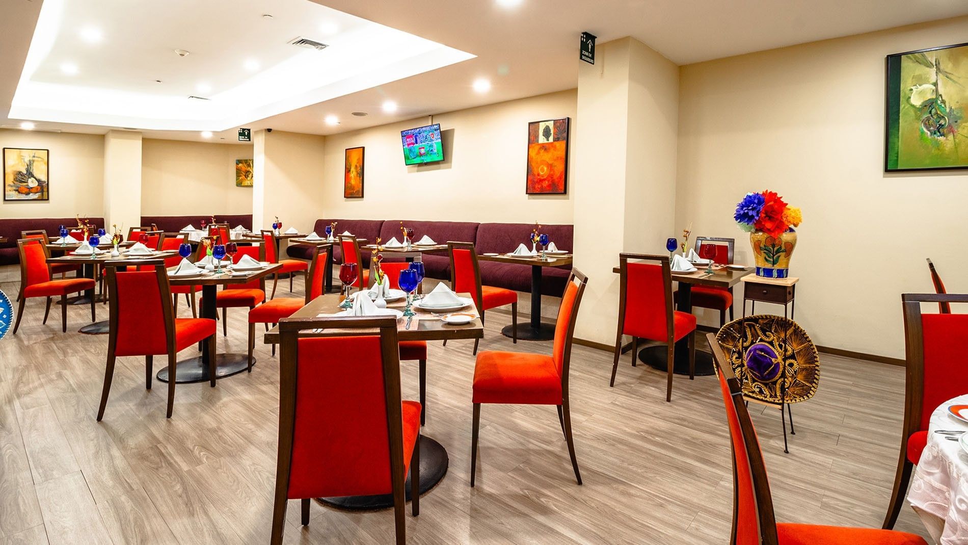 Elegante comedor con sillas rojas y mesas decoradas con vajilla lista para servir en Camino Real Aeropuerto México