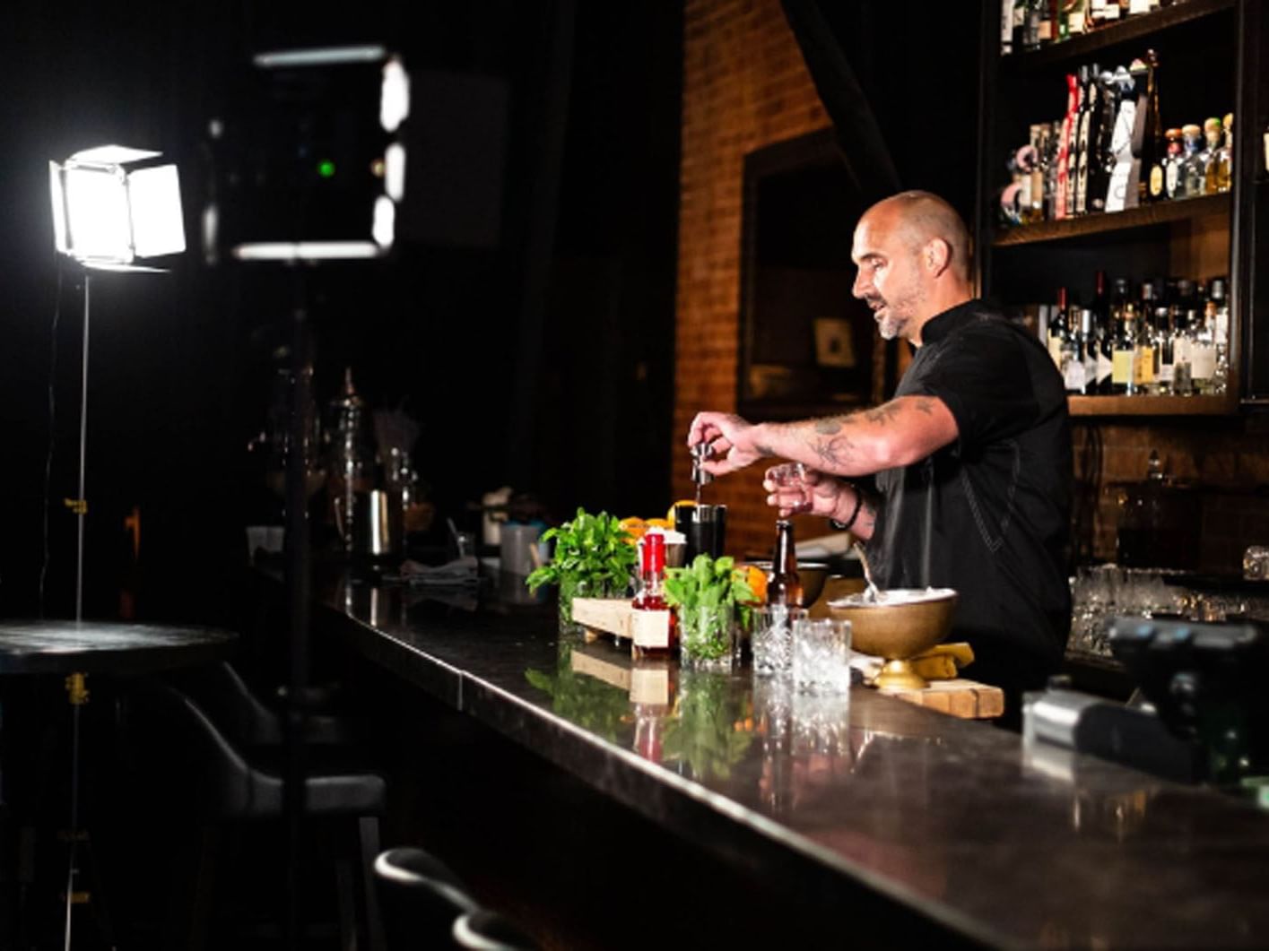 Frankie Solarik prepares drinks in a BarChef with lighting equipment in the foreground near Hotel X Toronto