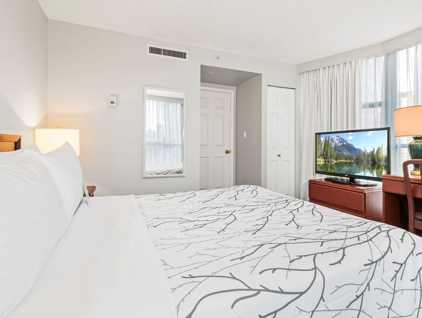 Workspace and nightstand by the neatly made cozy bed in a bedroom at Rosedale on Robson, featuring hotel suites in Vancouver