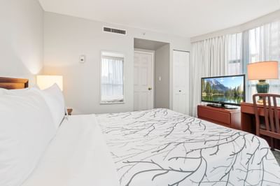 Workspace and nightstand by the neatly made cozy bed in a bedroom at Rosedale on Robson, featuring hotel suites in Vancouver