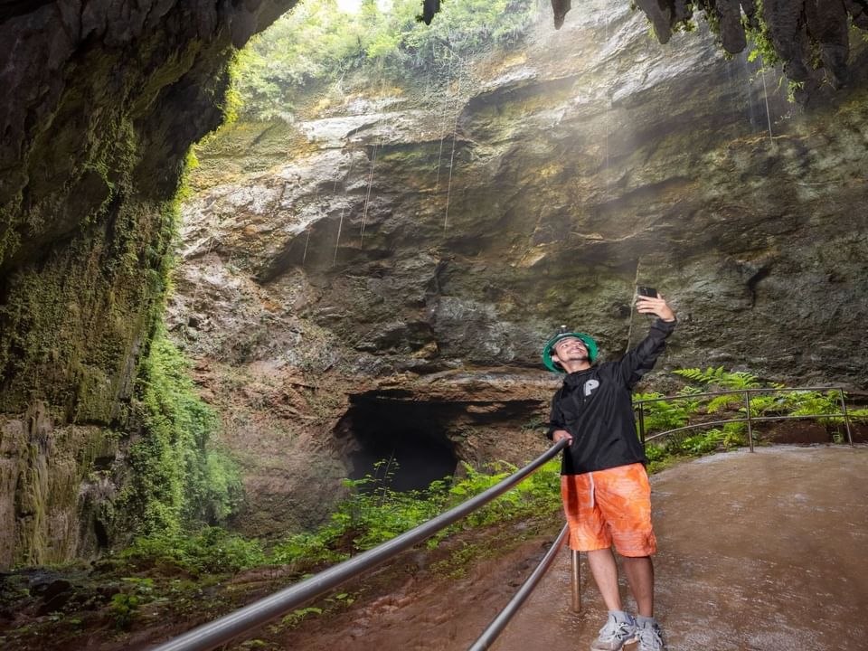 Man taking a selfie with the cave backdrop in Camuy River Cave Park near Las Casitas Village
