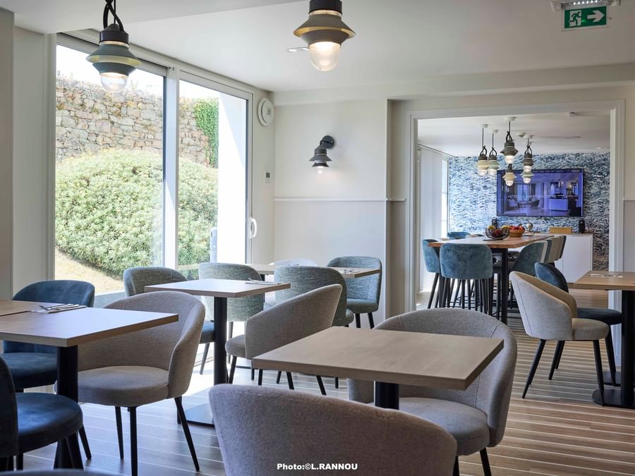 Tables et chaises dans un restaurant moderne avec vue sur la nature à l'Hôtel La Marébaudière.