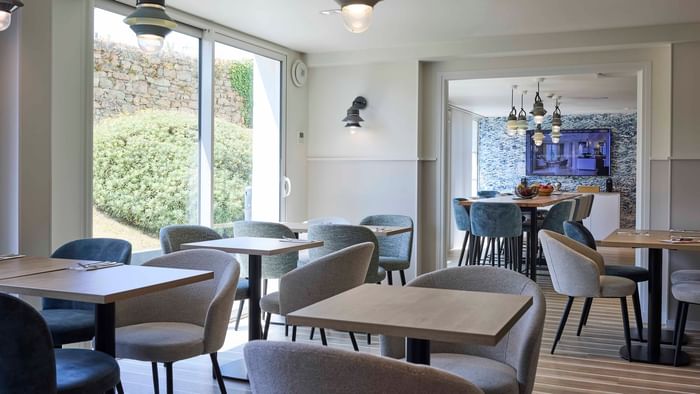 Tables et chaises dans un restaurant moderne avec vue sur la nature à l'Hôtel La Marébaudière.