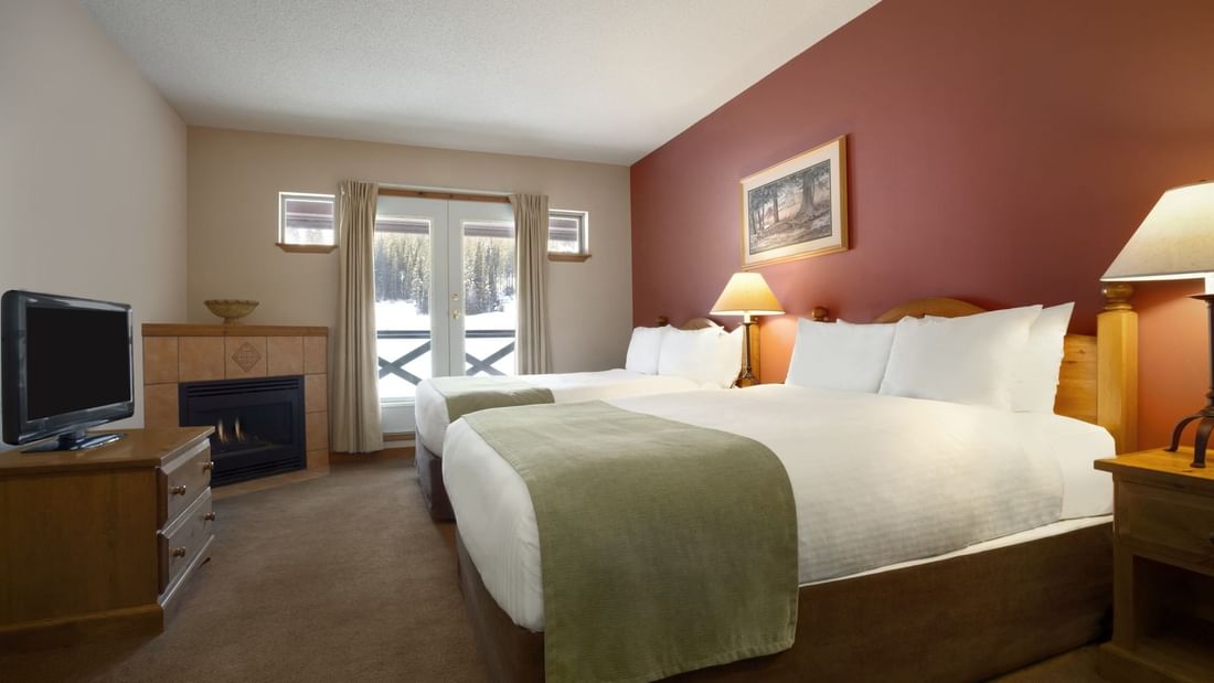 Two beds in hotel room with view of ski slopes