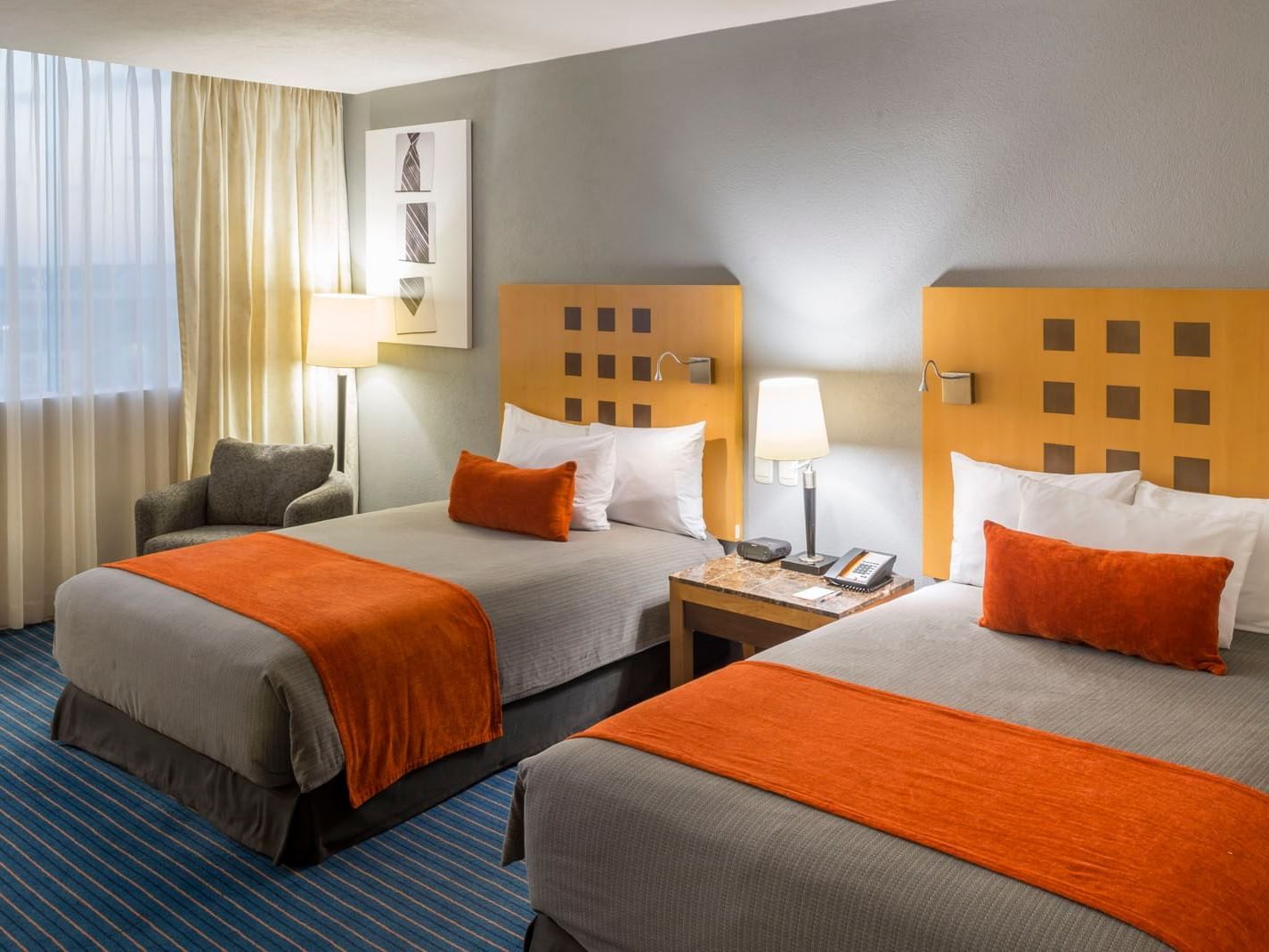 2 Double Deluxe featuring orange accents, wooden headboards, and a shared nightstand at Real Inn Nuevo Laredo