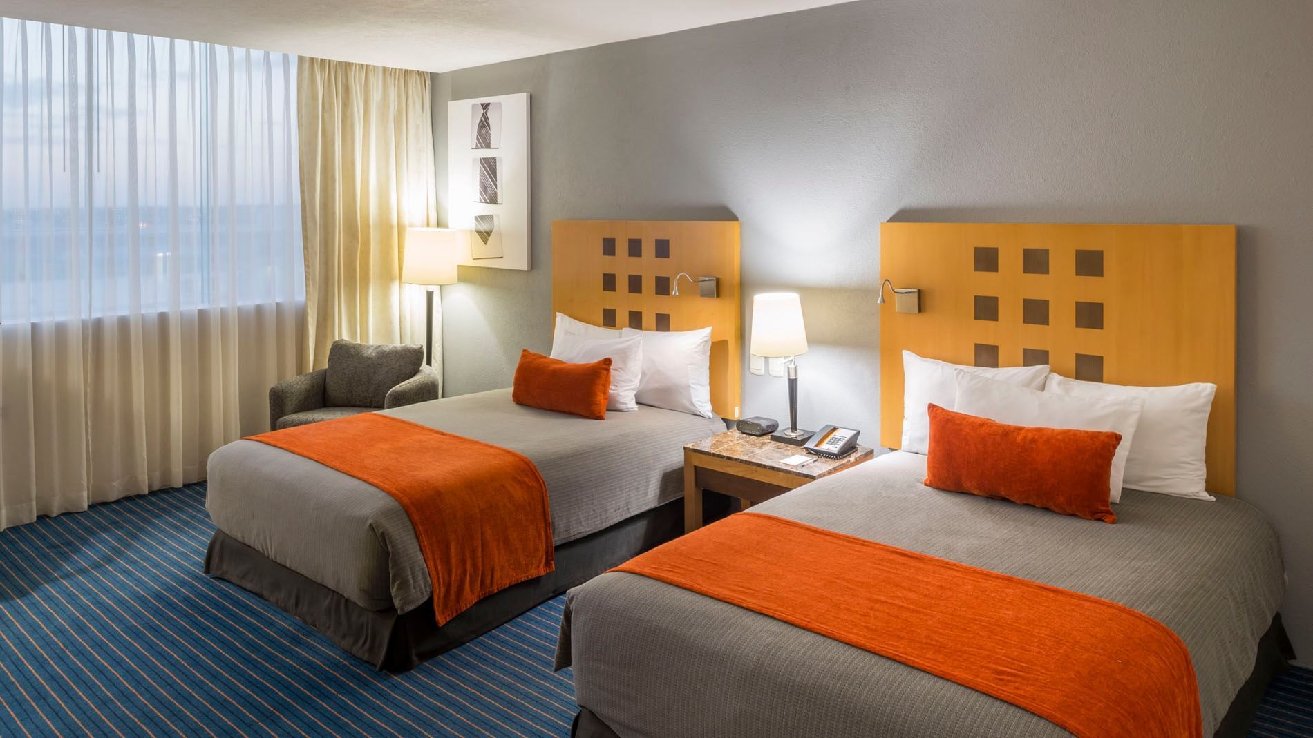 2 Double Deluxe featuring orange accents, wooden headboards, and a shared nightstand at Real Inn Nuevo Laredo