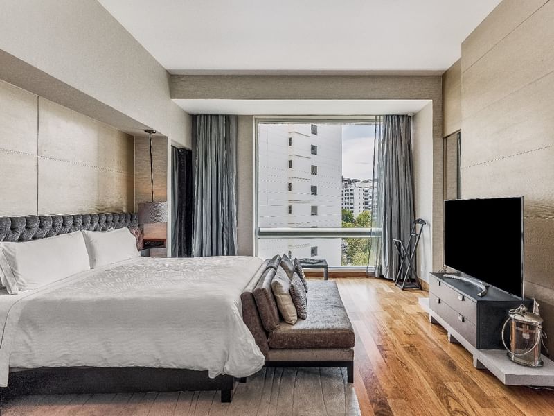 Comfy bed and TV with city view in Luna Presidential Suite at Fiesta Americana Travelty