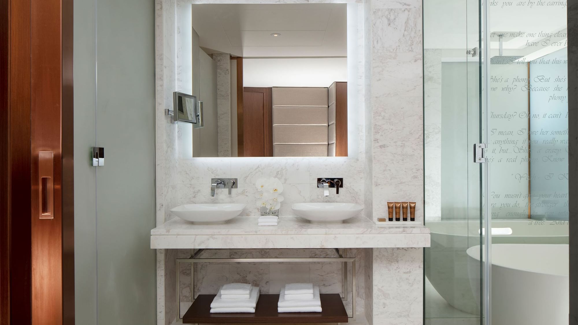 Vanity with large mirror and soft lighting by the glass shower in Scene Proscenium Room at Paramount Hotel Dubai