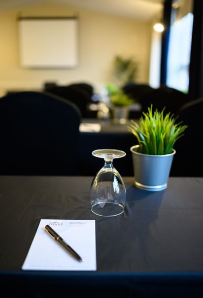 Pen and notepad beside an upside-down glass and potted plant on a conference table at Rodd Moncton
