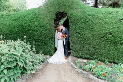Bride and groom kissing under a landscaped archway