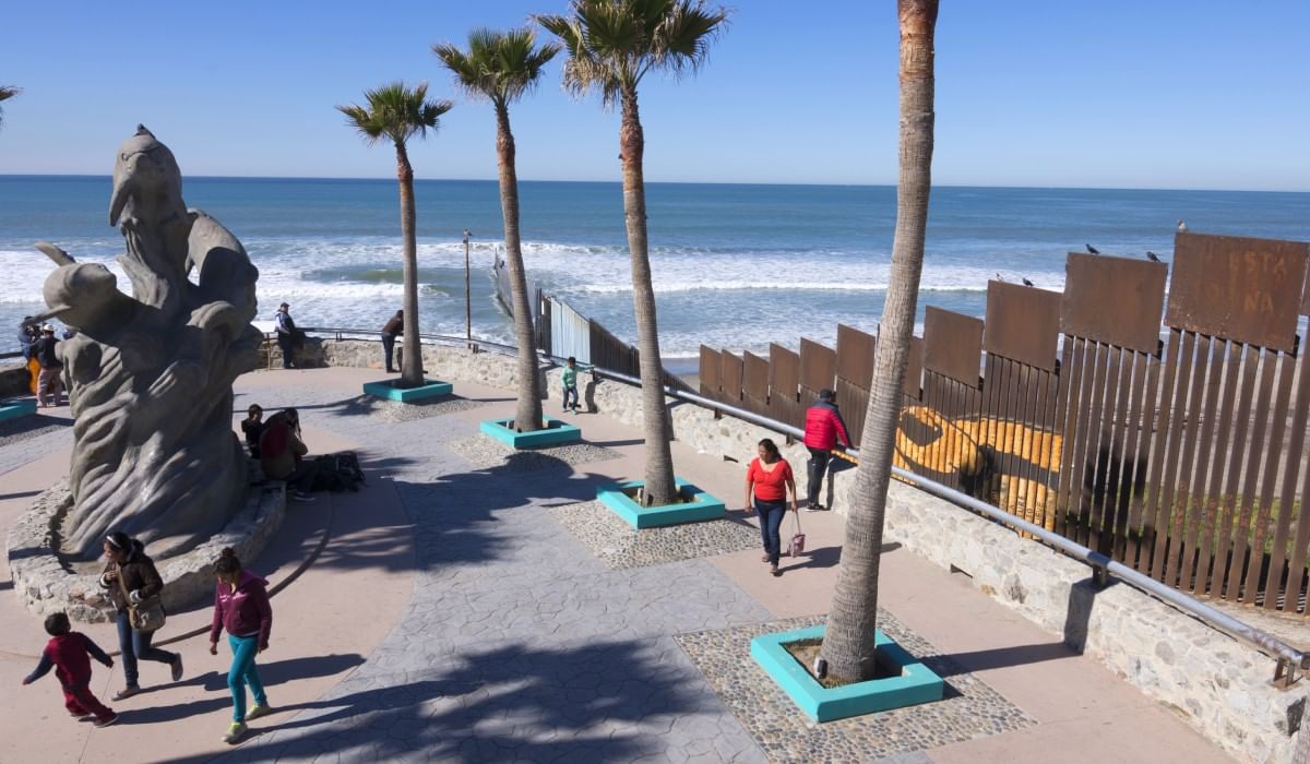 Personas caminando por sendero costero pavimentado con palmeras cerca de Camino Real Hotels