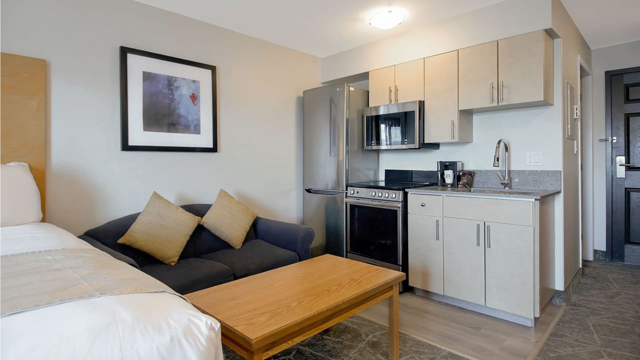 Room with king bed, couch and kitchen appliances