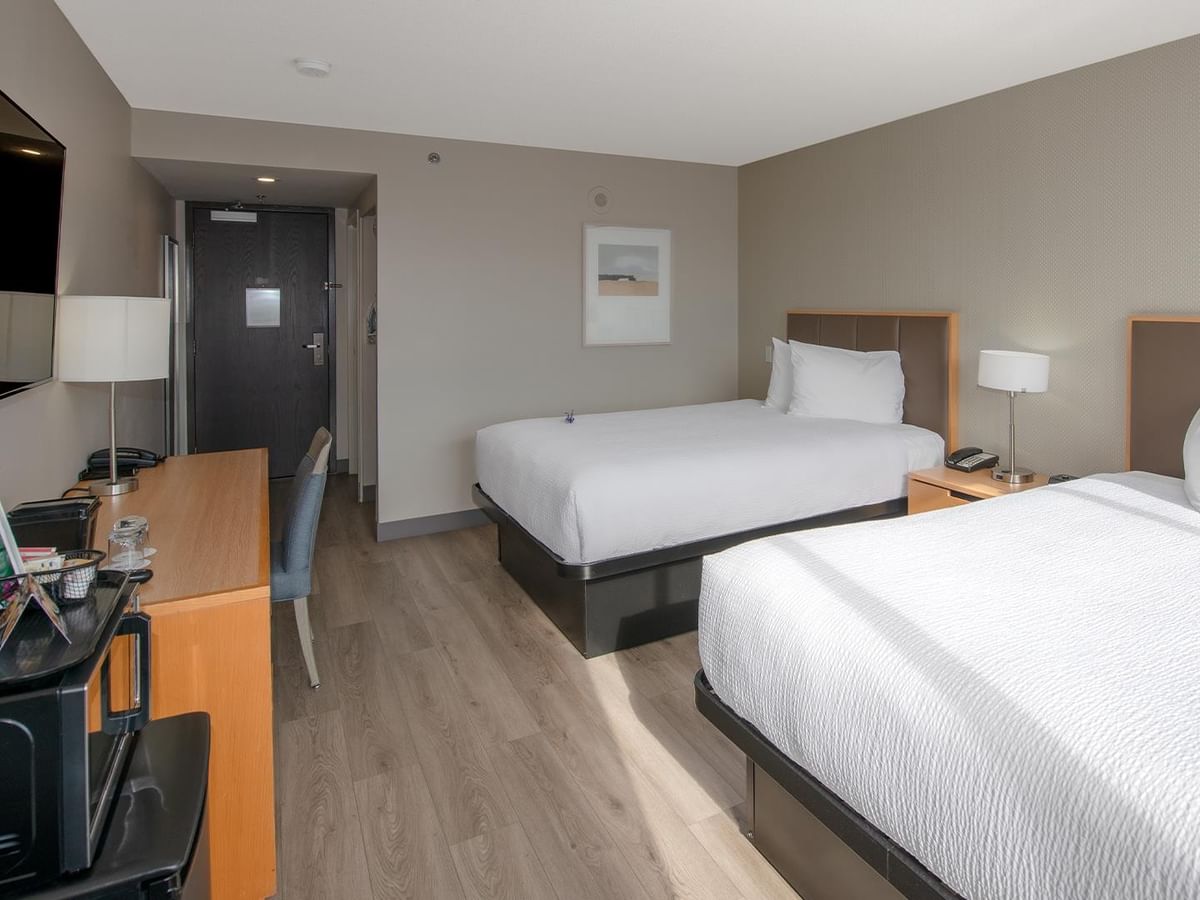 Two beds and a desk with a flat screen TV.