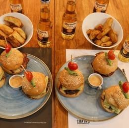 Mini burgers with fries and Corona beers arranged on a wooden table at Unika Hotels, Restaurant Bogota