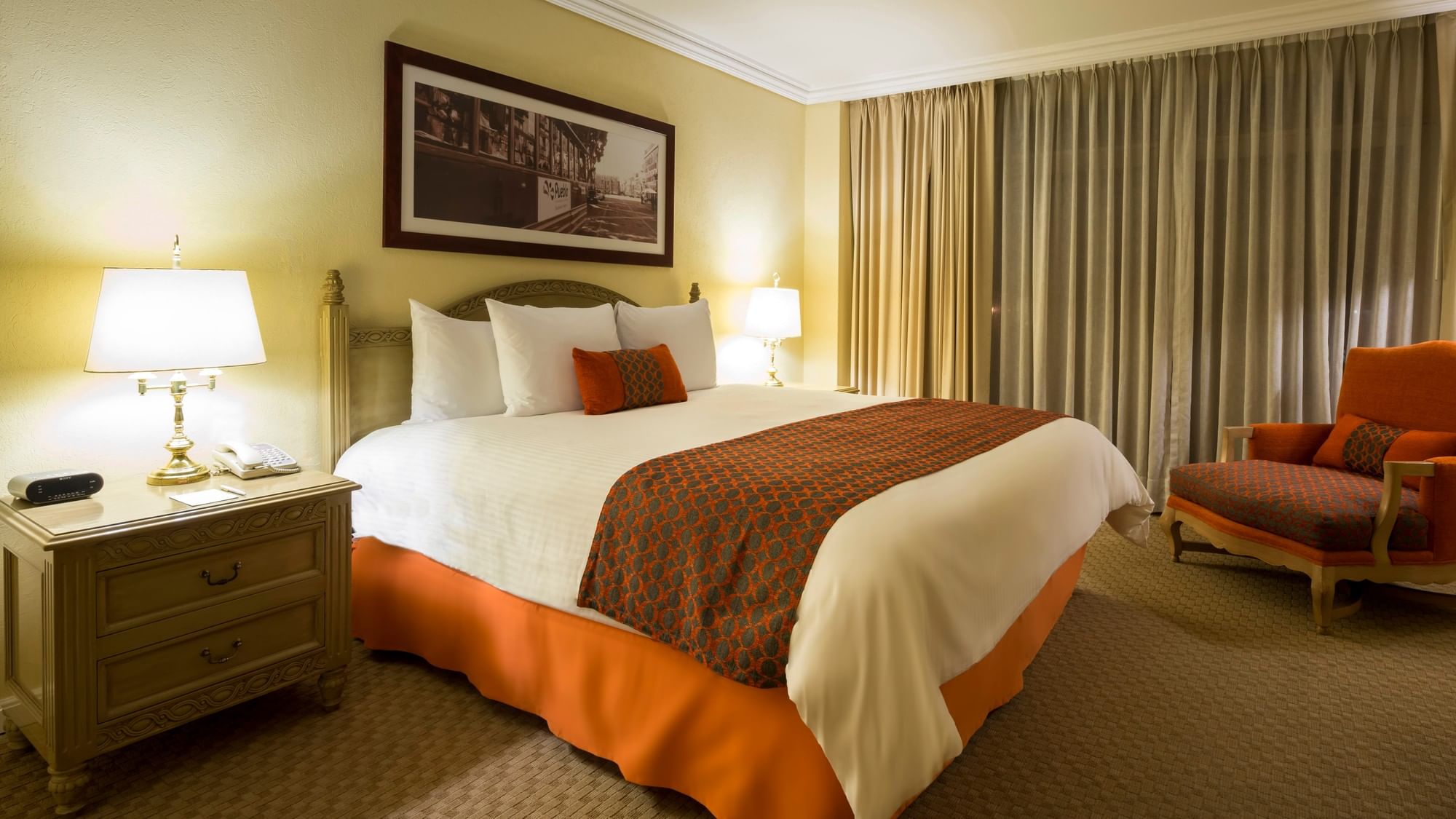 Spacious guest room with king bed, orange accents, and seating area at Camino Real Puebla Angelopolis