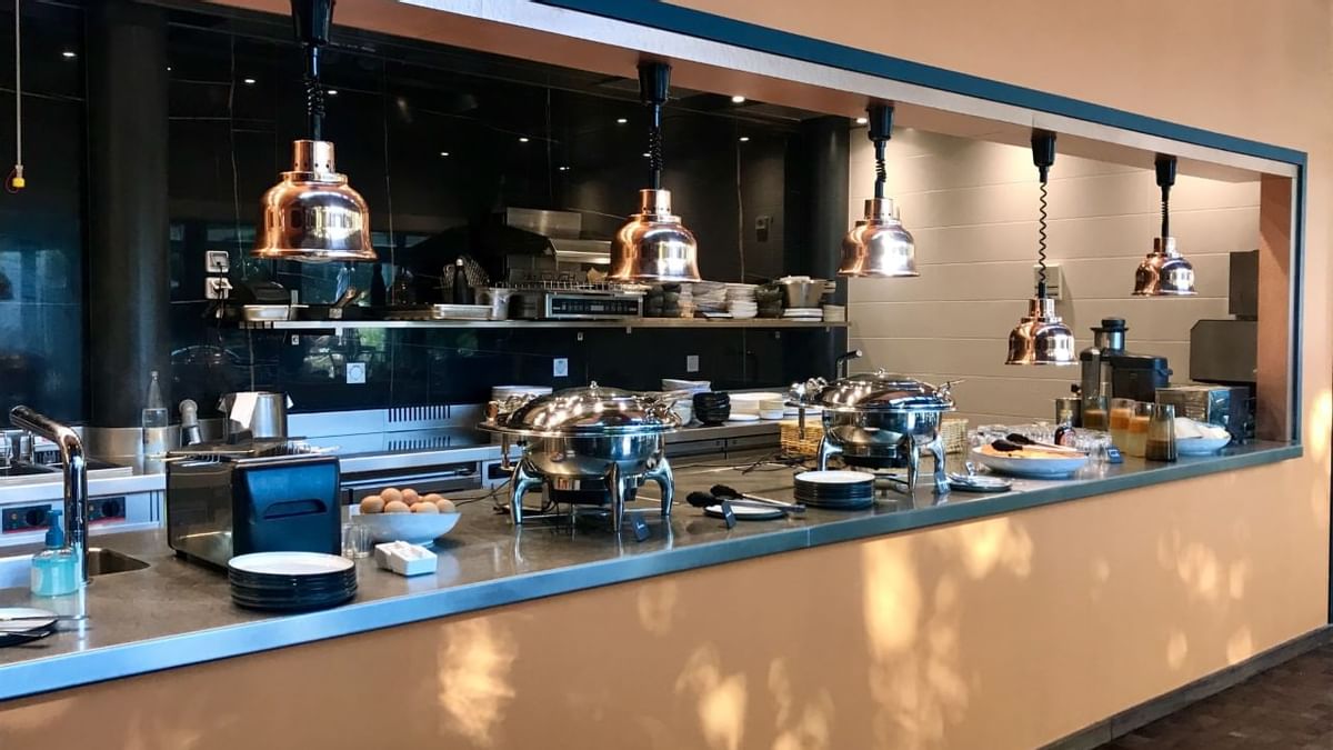 Buffet avec des plats, des ustensiles de cuisine, et des lampes suspendues dans une cuisine moderne.
