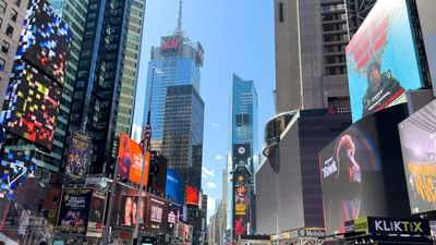 Times Square city street view with massive digital billboards by tall glass skyscrapers near Warwick Hotels & Resorts
