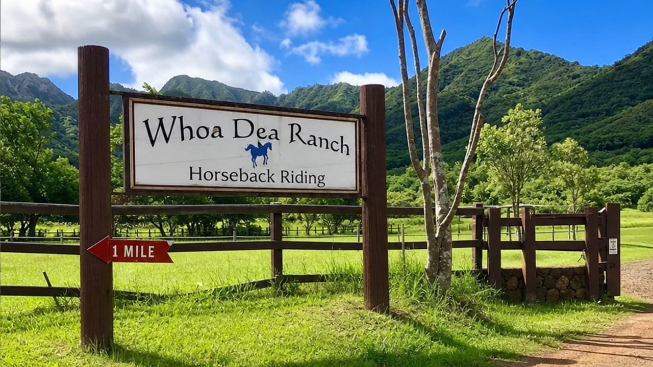 Wooden sign for Whoa Dea Ranch Horseback Riding with green mountains and pastures in the background under blue sky.