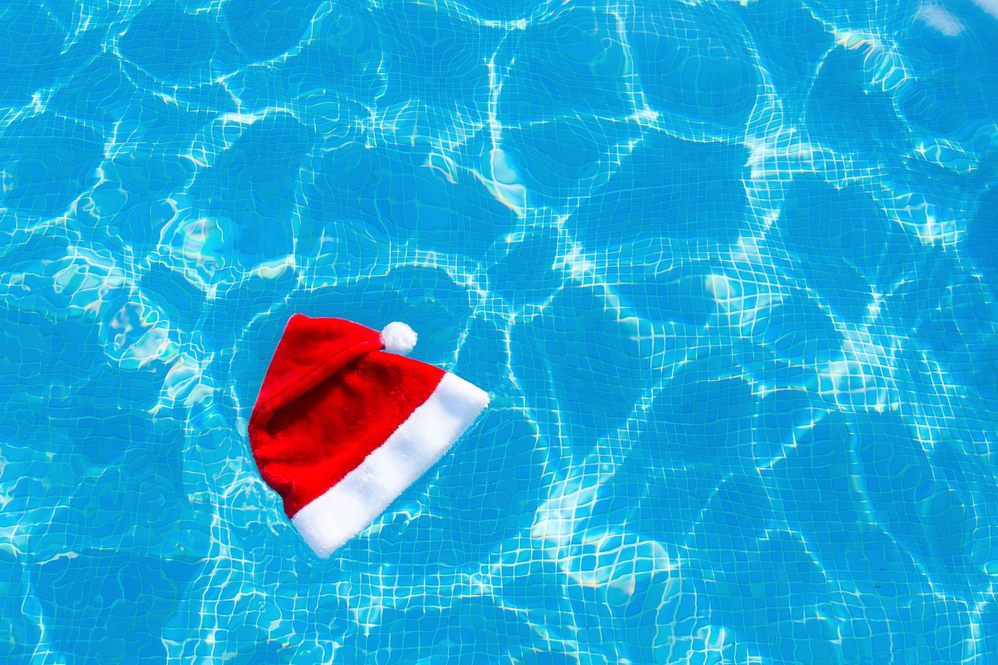 Red Santa hat floating on the clear blue pool, reflecting sunlight at Cove Pocono Resorts