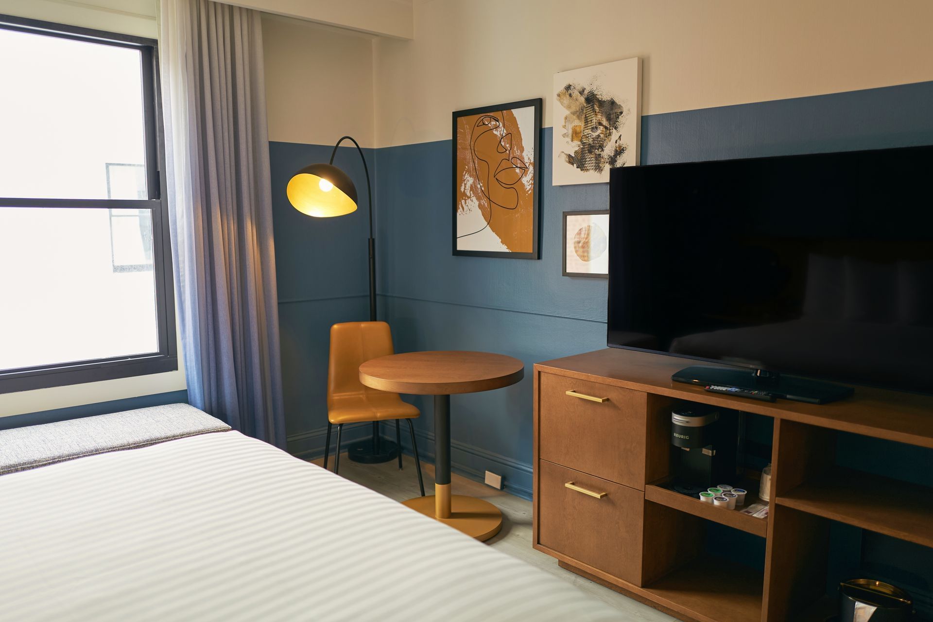 A hotel room with a bed, desk, chair, and TV.