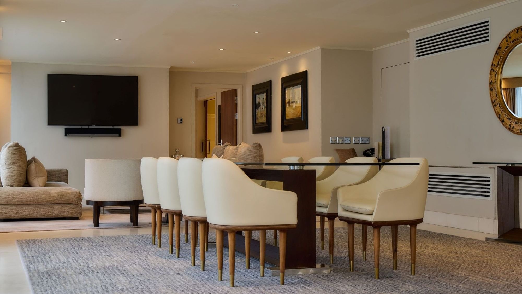 The Penthouse Suite features a spacious dining area with white upholstered chairs and modern decor at The May Fair Hotel, London.