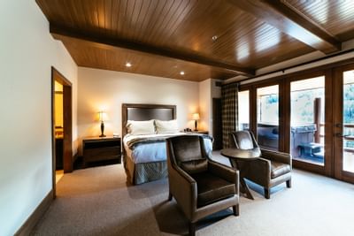 A double bed & 2 armchairs in a balcony room at Stein Lodge