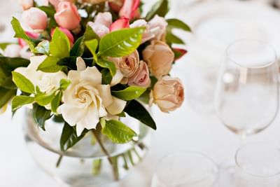 Close-up of a glass vase filled with white gardenias and pink roses on a table setting at Spencer Hotel & Conference Centre