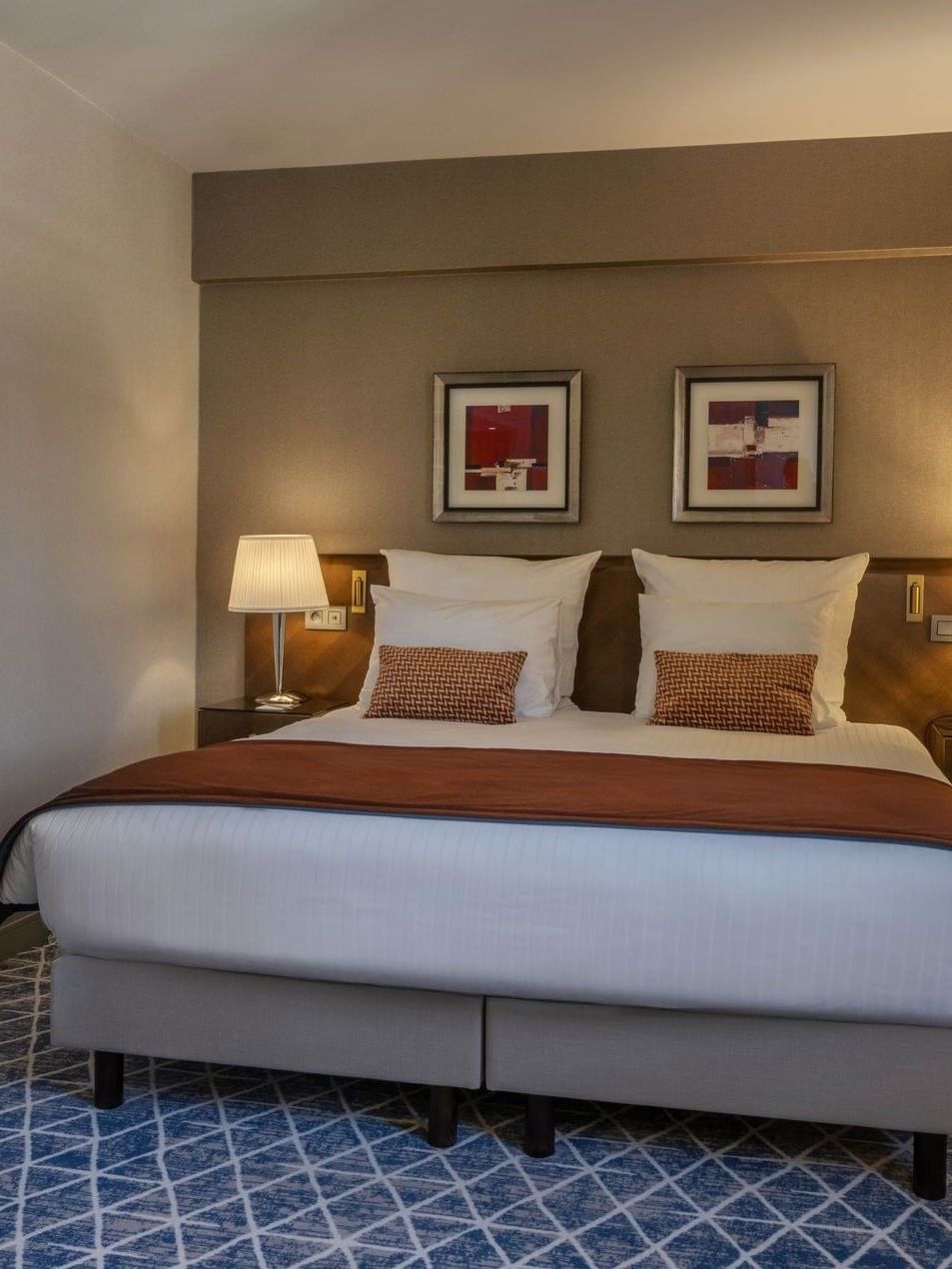 Bed with side tables and hanging wall art in Premium Deluxe Room at Warwick Grand Place Brussels