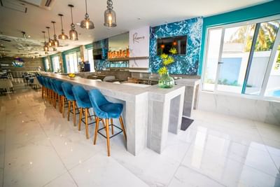 Modern marble Remous Bar with blue velvet stools and ocean-themed wall art at The Abidah Hotel by Accra