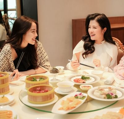 Three women enjoying dim sum and shrimp spring rolls in Ngan Dinh Hanoi Restaurant at Hanoi Daewoo Hotel