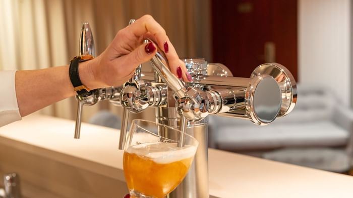 A maid pouring beer into the glass at Hotel acadine