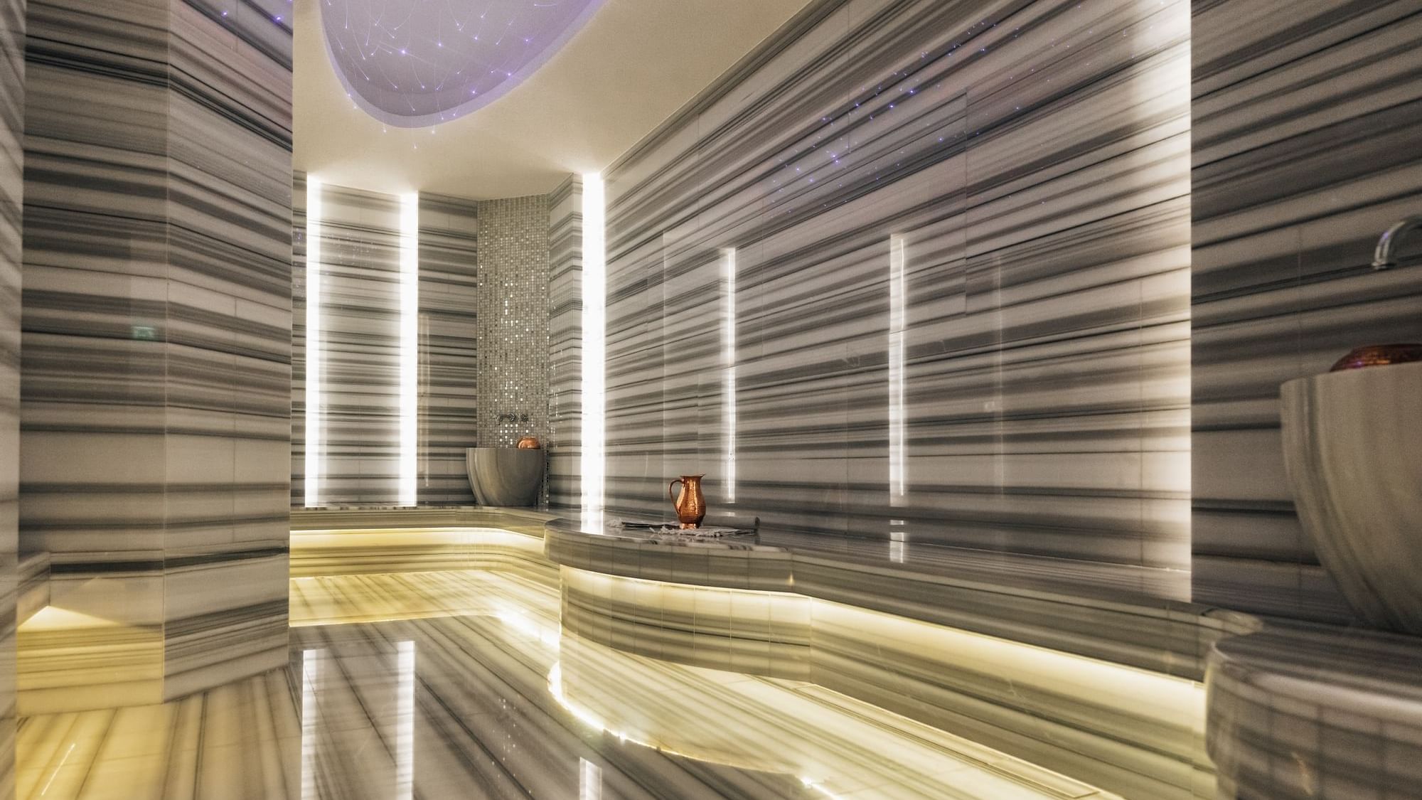 Serene white marble Turkish bath featuring a traditional fountain at Paramount Hotel Dubai