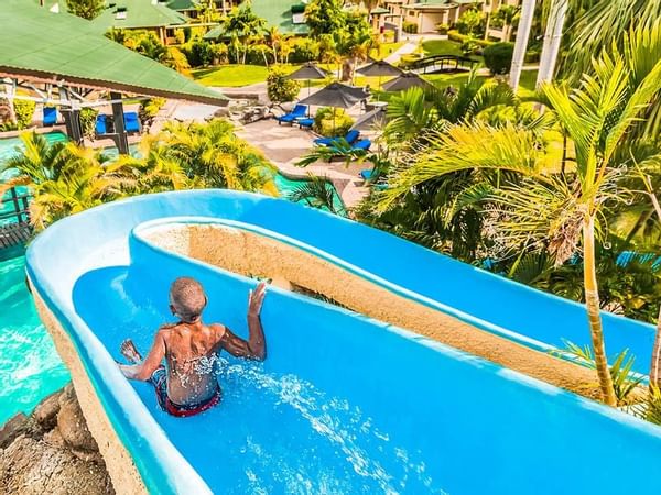 A kid enjoying the water slide in the pool at Tokatoka Resort