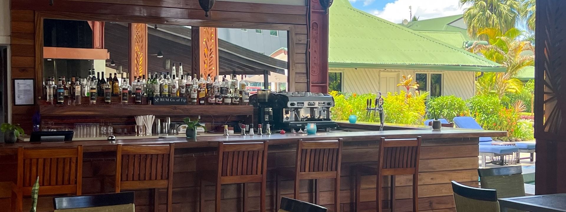 Bar with many liquor bottles and seating under hanging lanterns in an open-air pavilion at Tokatoka Resort in Nadi.