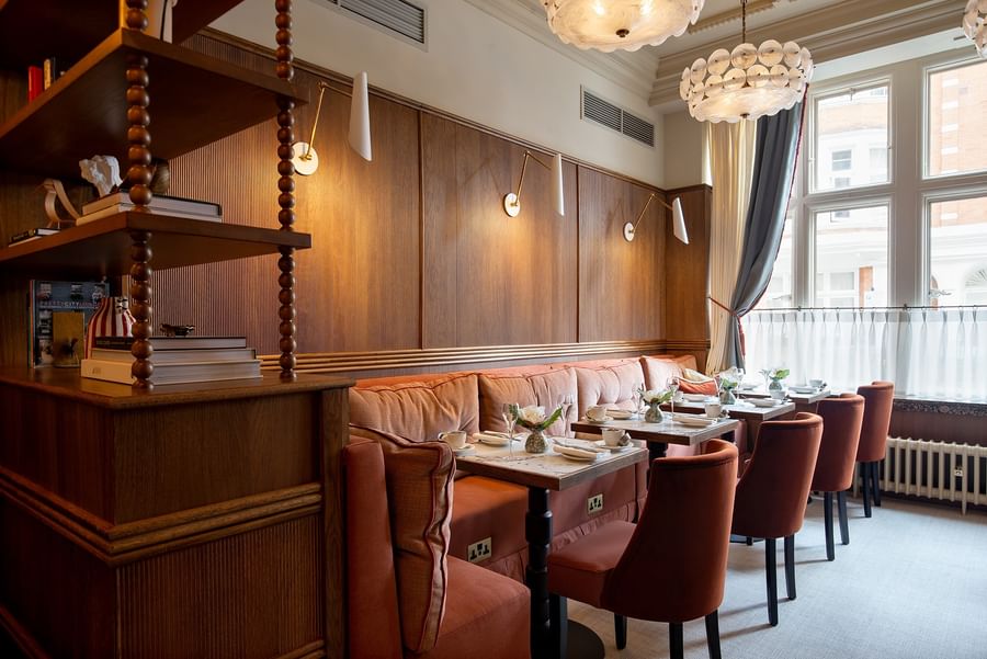 Dining tables set by cushioned orange seating under wall sconces at The Capital Hotel, Apartments and Townhouse
