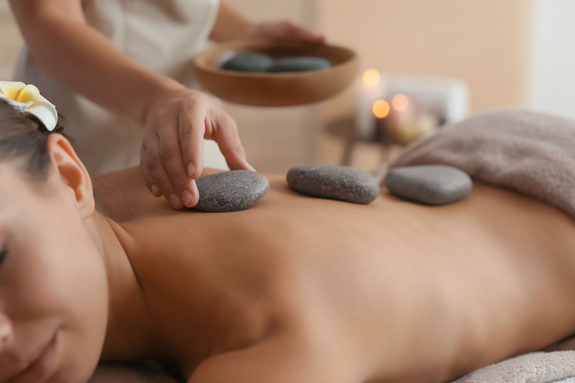 Lady receiving a hot stone treatment in Le Spa at The Spa by Warwick Melrose