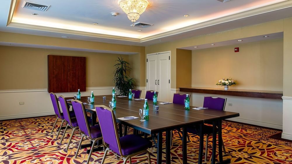 Purple chairs by a wood table under a crystal chandelier near a potted plant in Cambridge at Warwick Denver