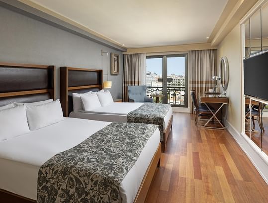 Two large beds, desk, chair, and Istanbul city views in Family Room at Titanic City Taksim.