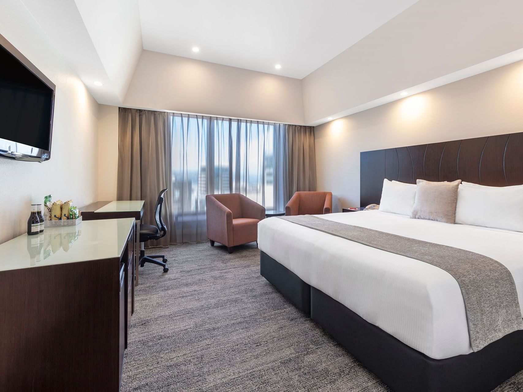 King bed, working desk, TV, and comfy chairs in Executive King at James Cook Hotel Grand Chancellor