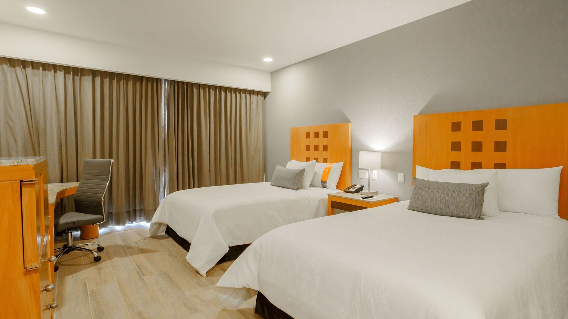 2 Double Deluxe room featuring two double beds with orange headboards and a dedicated workspace at Real Inn Torreon