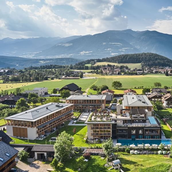 Aerial view of a Falkensteiner Family Resort Lido amidst greenery with mountains in the background