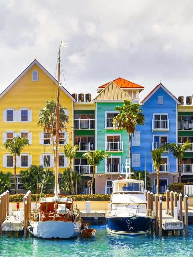 Vibrant buildings by a harbor under a cloudy sky surrounding docked boats at Warwick Paradise Island Bahamas