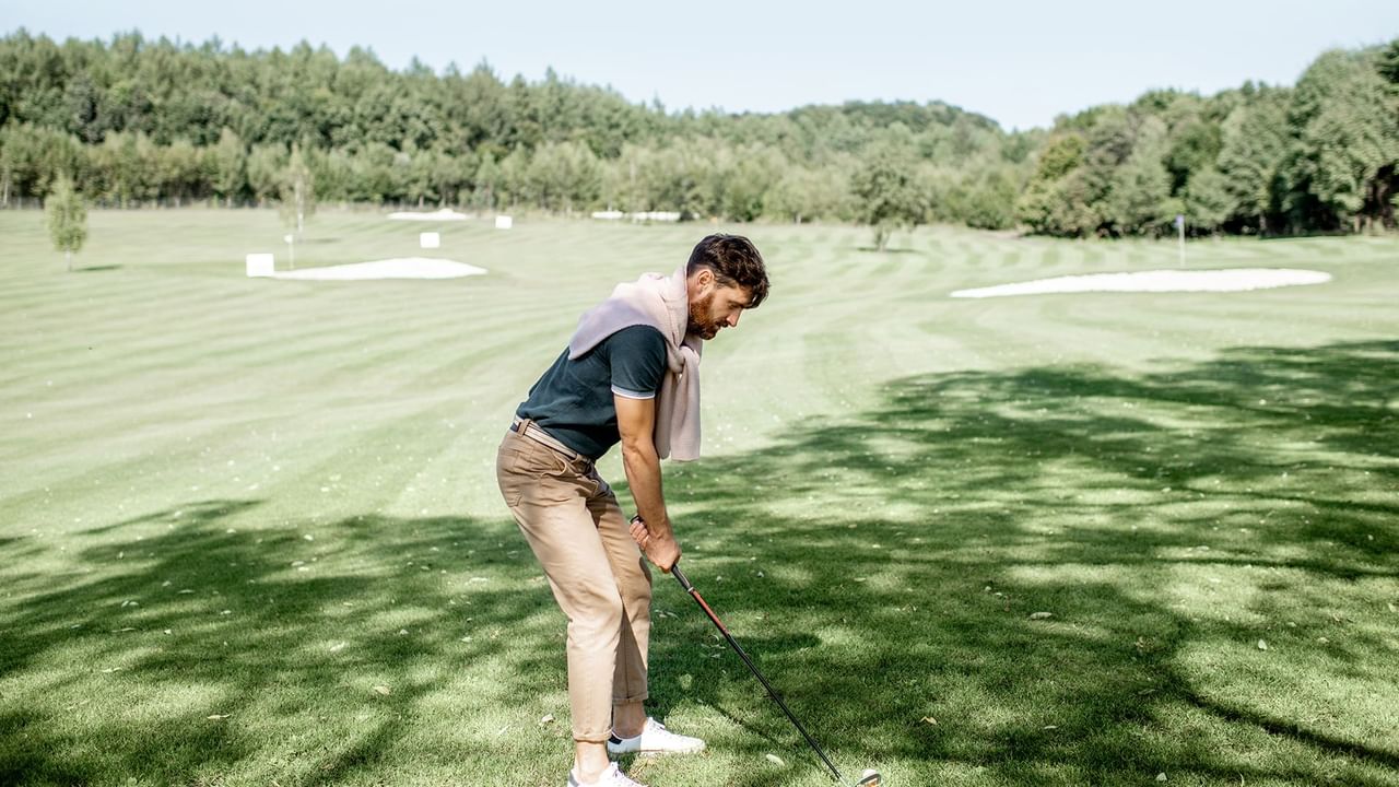 Person golfing in a golf course with lush greenery at Listel Whistler, a Coast Hotel